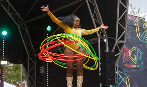 A woman performs with many hula hoops on stage.